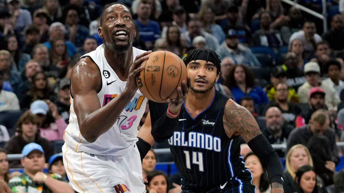 Miami Heat center Bam Adebayo (13) takes a shot in front of Orlando Magic’s Gary Harris (14) during the first half of an NBA basketball game, Saturday, Feb. 11, 2023, in Orlando.