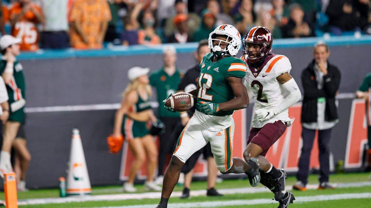 Miami Hurricanes wide receiver Brashard Smith (12) runs for touchdown against Virginia Tech Hokies defensive back Jermaine Waller (2) during the second quarter of their ACC football game at Hard Rock Stadium on Saturday, November 20, 2021 in Miami Gardens, Florida.