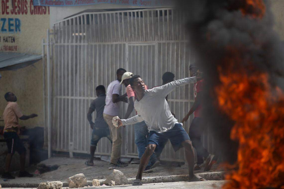 A protester throws a stone at police during a protest over the death of journalist Romelson Vilcin in Port-au-Prince, Haiti, Sunday, Oct. 30, 2022.