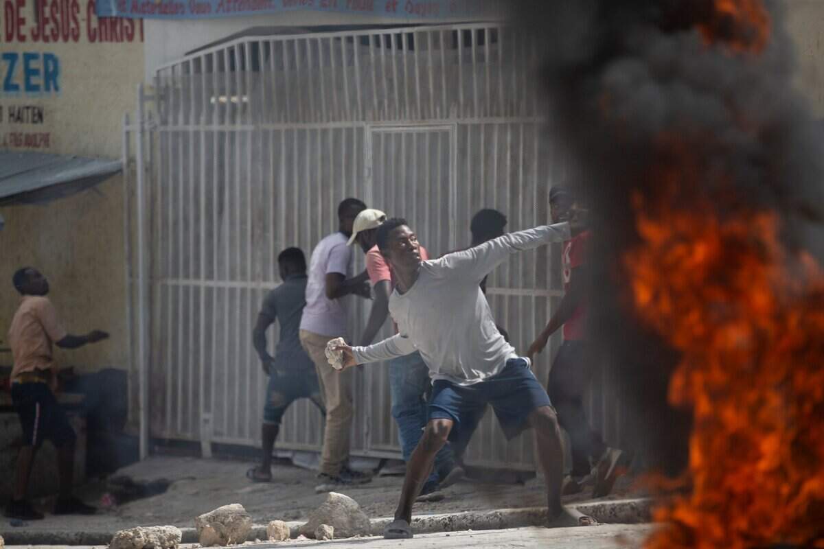 A protester throws a stone at police during a protest over the death of journalist Romelson Vilcin in Port-au-Prince, Haiti, Sunday, Oct. 30, 2022.