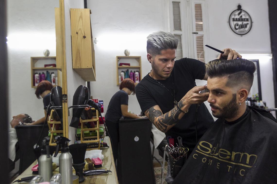 Alberto Carlos Bosch Rosquete, 30, a part-owner of the Barber Color shop, cuts a customer’s hair in Havana.