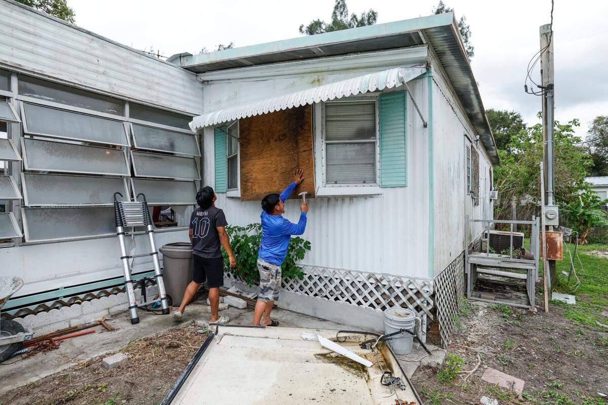 A medida que se acerca el huracán Milton, Juan Alonso, de 19 años, y Andrés Alonso, de 29, se preparan para proteger su casa, ya dañada por el huracán Helene, en Fairmont Mobile Home Estates en Ruskin, Florida, el martes 8 de octubre de 2024.