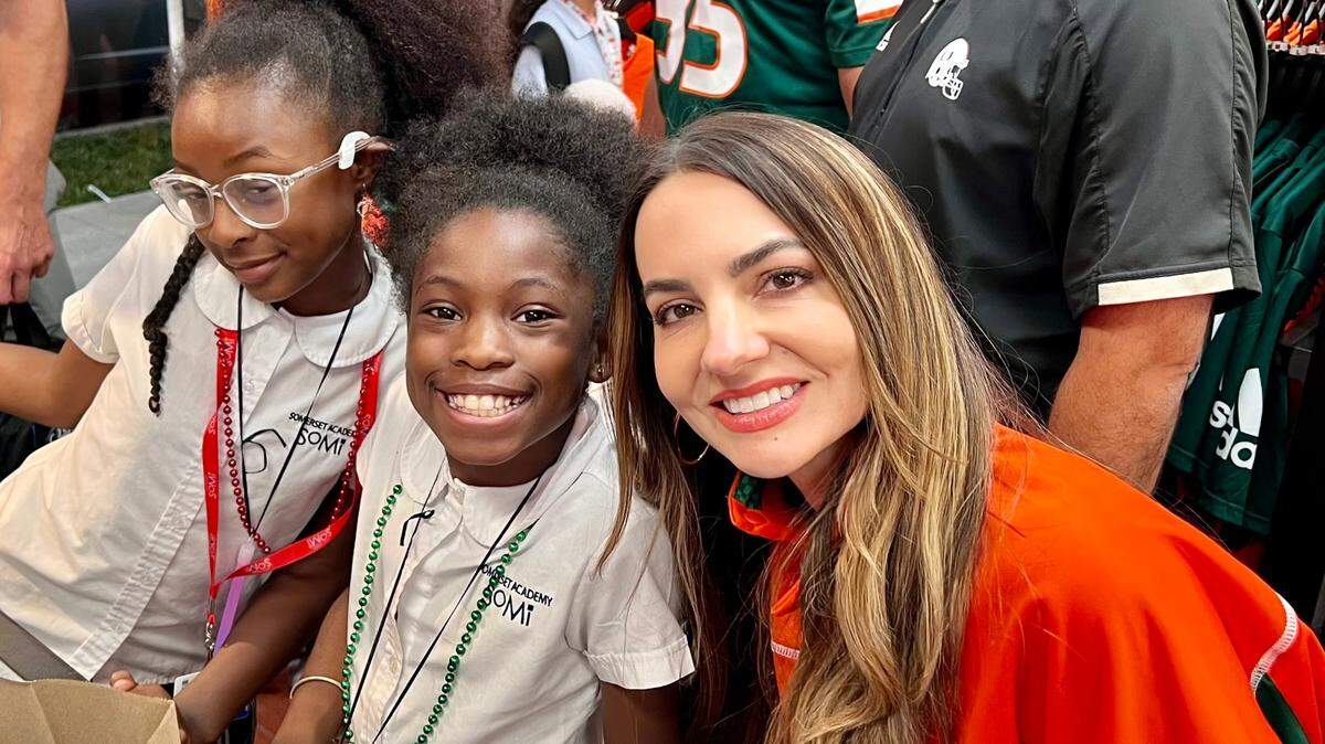 Jessica Cristobal, the wife of UM football coach Mario, is shown with two children from the Police Athletic League at the 2022 allCanes Holiday Shopping Spree to honor the legacy of Bryan Pata.