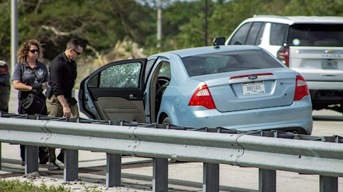 Florida Highway Patrol investigators look over a bullet-riddled blue Ford Fusion on the side of Florida’s Turnpike at the Campbell Drive exit near Homestead Friday morning, March 1, 2024.
