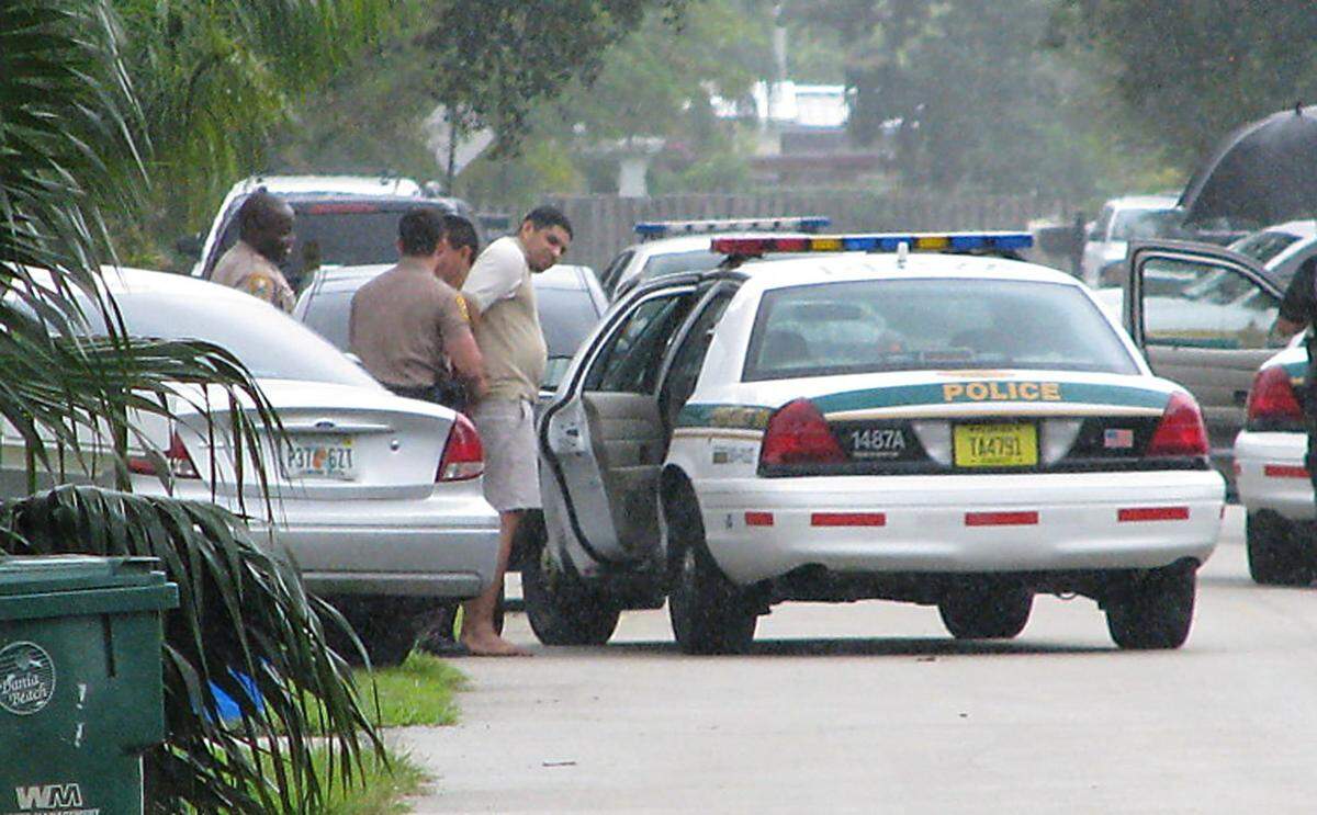 In 2008, police officers take suspects into custody near a police car.