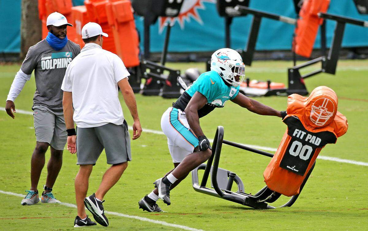Miami Dolphins coaches watch as Miami Dolphins cornerback Noah Igbinoghene (19) goes through a tackling drill during Day 3 of NFL training camp.