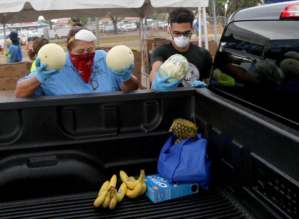 Ana Hernandez and Carlo Rodriguez were among volunteers and city of Miami employees loading food and vegetables into hundreds of cars lined up for hours April 11 at a food giveaway.