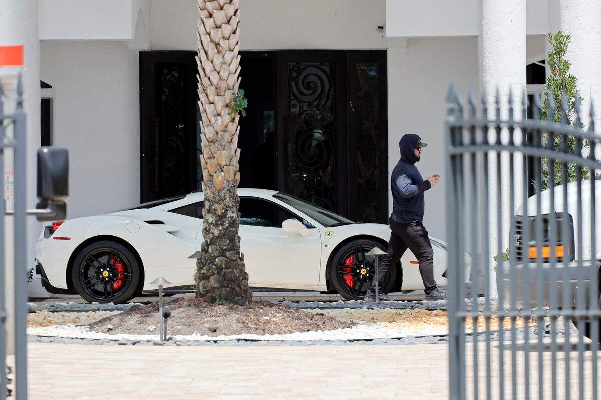 A man walks past a Ferrari in the driveway at Sean Kingston’s Southwest Ranches home on Thursday, May 23, 2024. A woman named Janice Turner, 61, was arrested on “numerous fraud and theft charges,” during the raid at the sprawling white mansion in the 4600 block of Southwest 178th Avenue, spokesperson Carey Codd said in a media release. Turner is Kingston’s mother, according to reports. (Amy Beth Bennett / South Florida Sun Sentinel)
