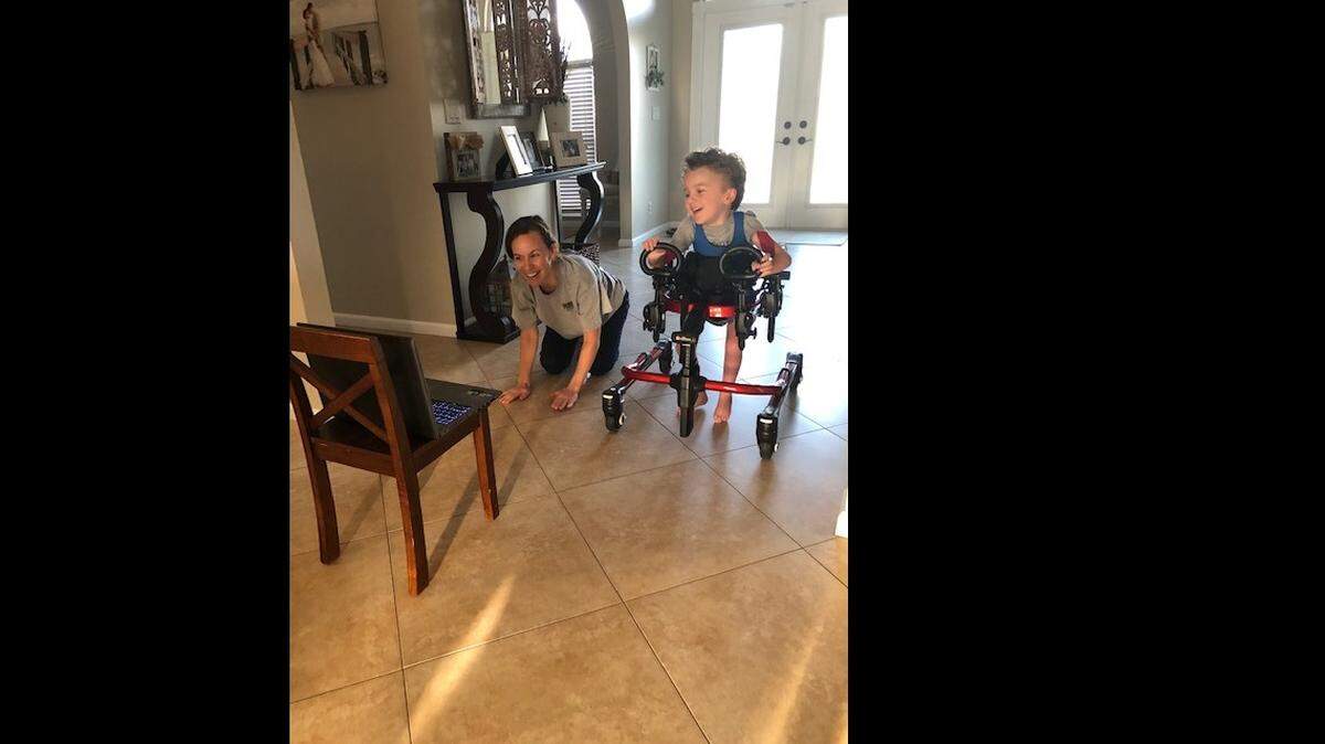 Parker Royal, 4, with his mom, Allie, has adjusted to physical therapy by laptop.