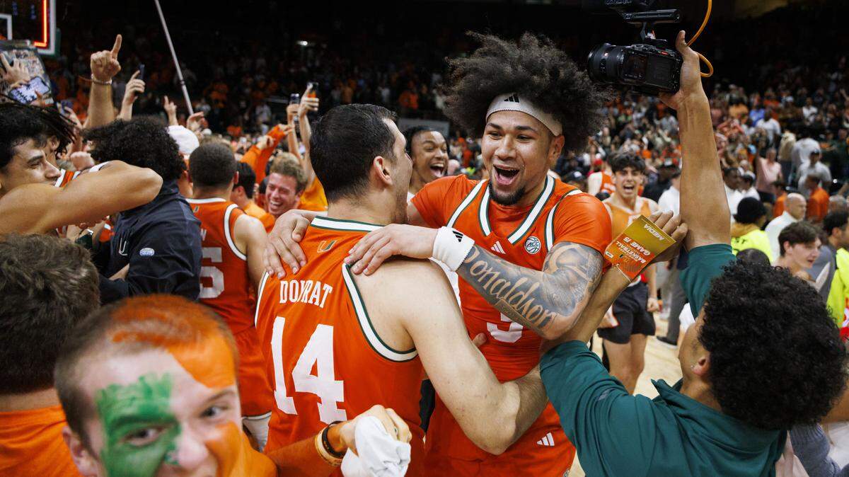 Miami Hurricanes guard Tre Donaldson (3) celebrates with guard Noam Dovrat (14) after fans stormed the court when the Miami Hurricanes beat the North Carolina Tar Heels 75-66 on Tuesday, Feb. 10, 2026, at the Watsco Center in Coral Gables, Fla.