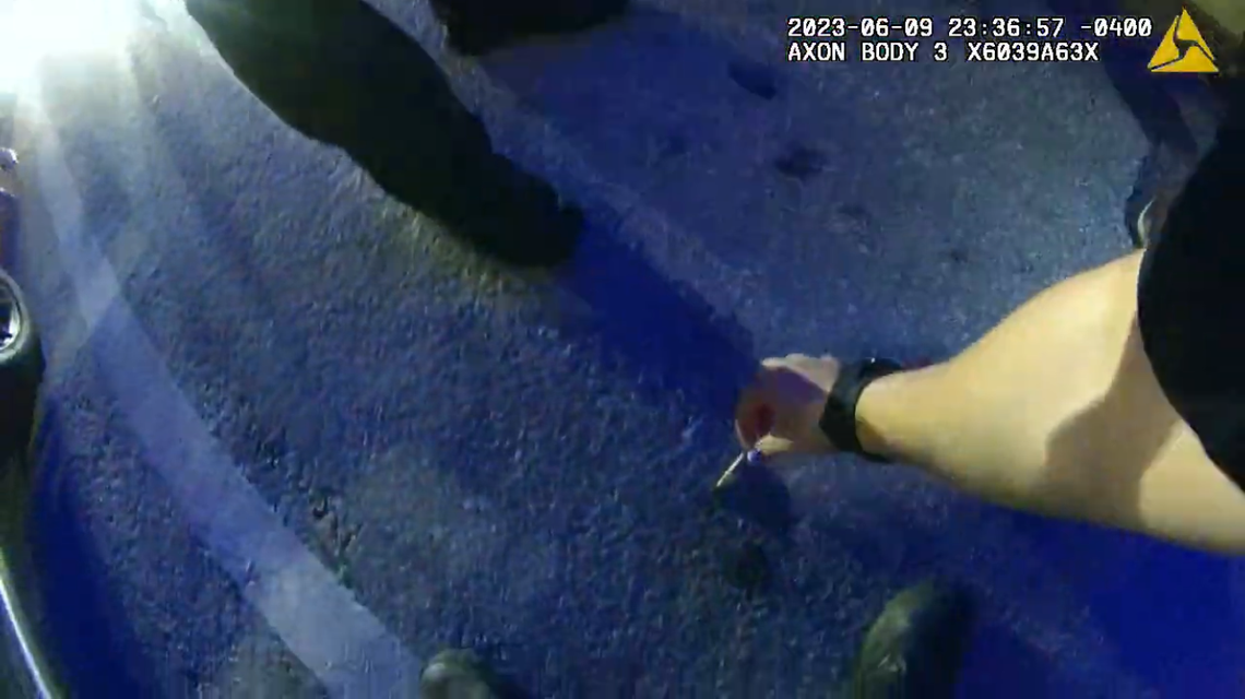 A Miami Beach police officer picks up a joint she said Fred Johnson threw from a golf cart on Ocean Drive on June 9, 2023.
