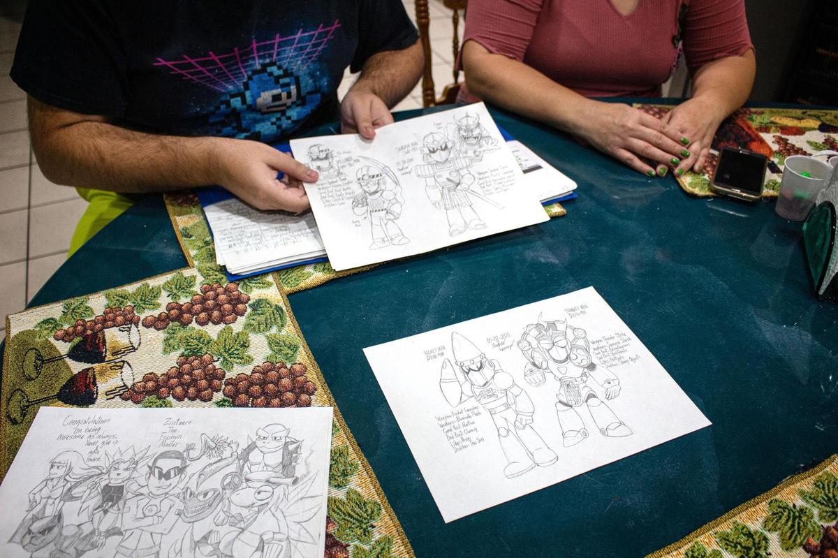 Andres Lorenzo, 22, flips through his illustrations with his mother, Sady Lorenzo, in their kitchen. Andres says creating art is a way of expressing himself and unwinding.