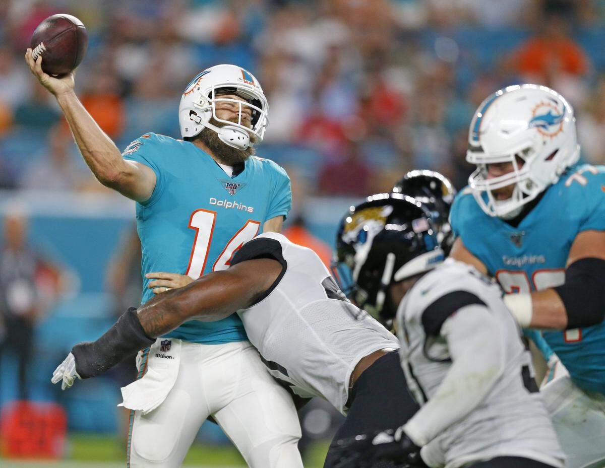 Miami Dolphins quarterback Ryan Fitzpatrick (14) gets hit as he attempts to pass in the first quarter as the Miami Dolphins host the Jacksonville Jaguars at Hard Rock Stadium on Thursday, August 22, 2019.