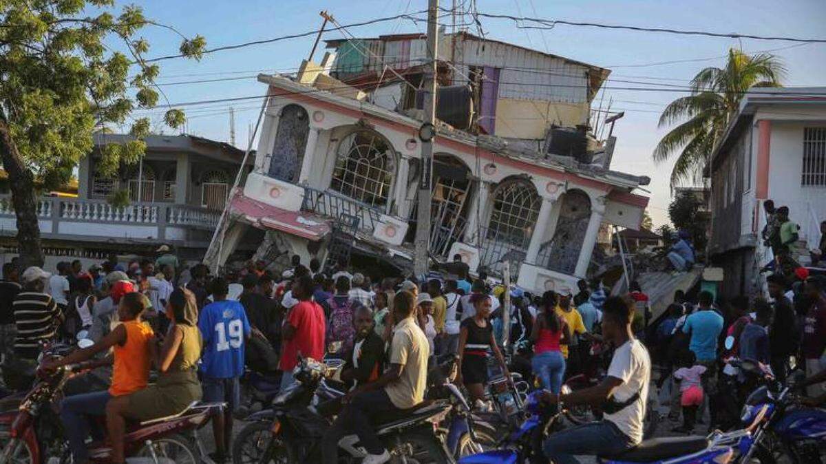 People gather outside the Petit Pas Hotel, destroyed by a 7.2 magnitude earthquake in Les Cayes, Haiti, in August 2021.