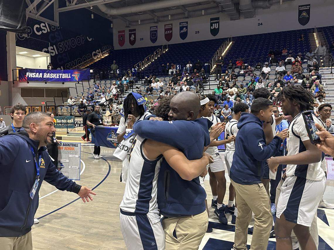 St. Thomas Aquinas coach Julius Sandi shares a hug with his son, Raiders guard DJ Sandi, after winning the Class 6A state boys’ basketball championship on Saturday at UNF Arena in Jacksonville, Fla.