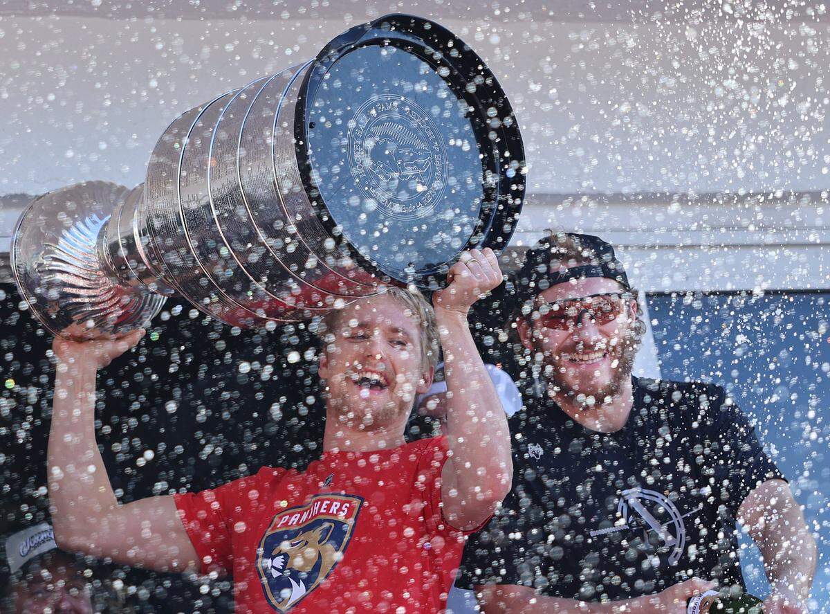 Gustav Forsling, left, raises the Stanley Cup as he and Matthew Tkachuk, right, celebrate in a haze of bubbles .