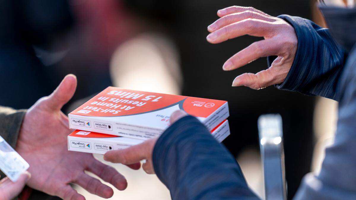 In this stock photo, a worker hands out boxes of at-home Covid-19 test kits to people who waited in a long line that snakes multiple times around the Shaw Library in Washington, Wednesday, Dec. 22, 2021.
