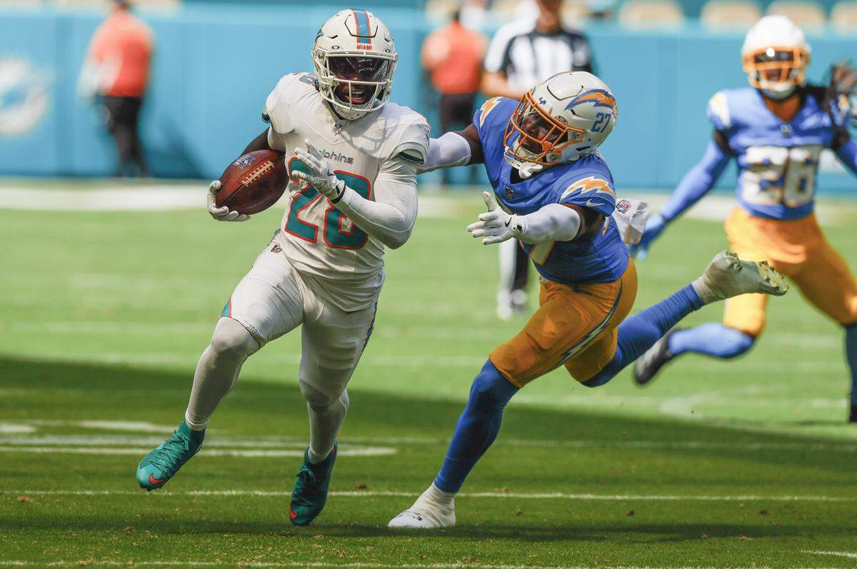 Miami Dolphins running back De'Von Achane (28) runs into score as Los Angeles Chargers safety R.J. Mickens (27) gives chase in the first half during their NFL football game at Hard Rock Stadium in Miami Gardens, FL, on Sunday, October 12, 2025. 