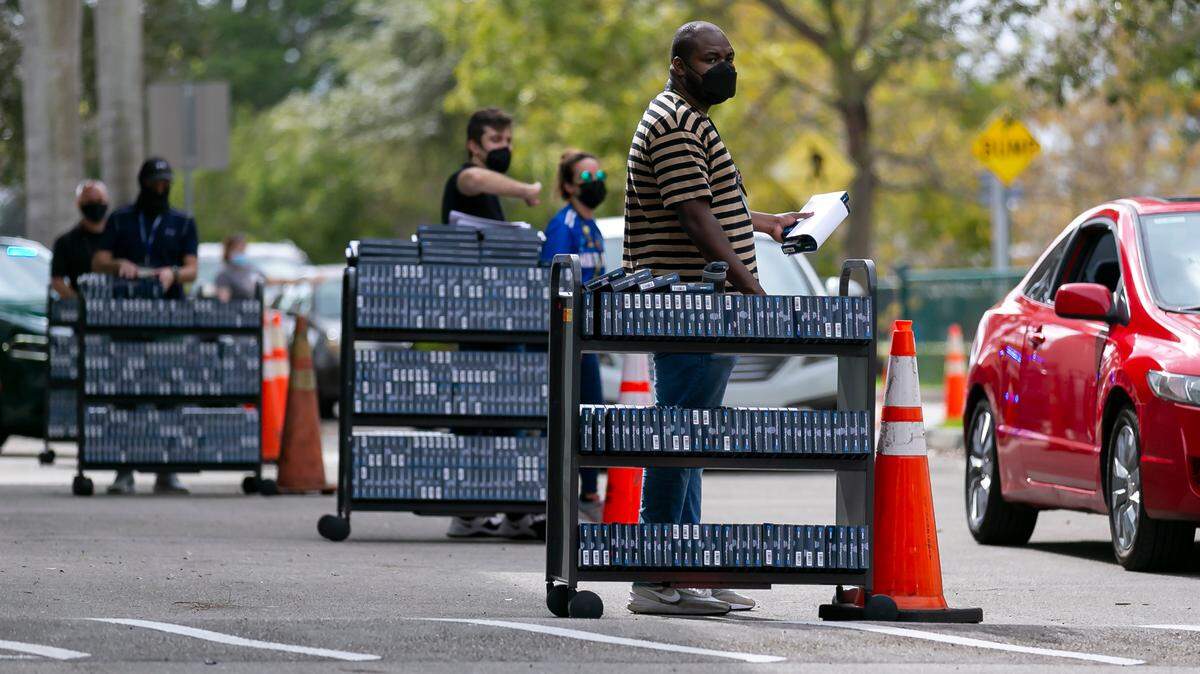 Jefferey Florvil, empleado del Condado Browad, distribuye gratis kits caseros de la prueba casera dek COVID en Pembroke Pines el 8 de enero de 2022.