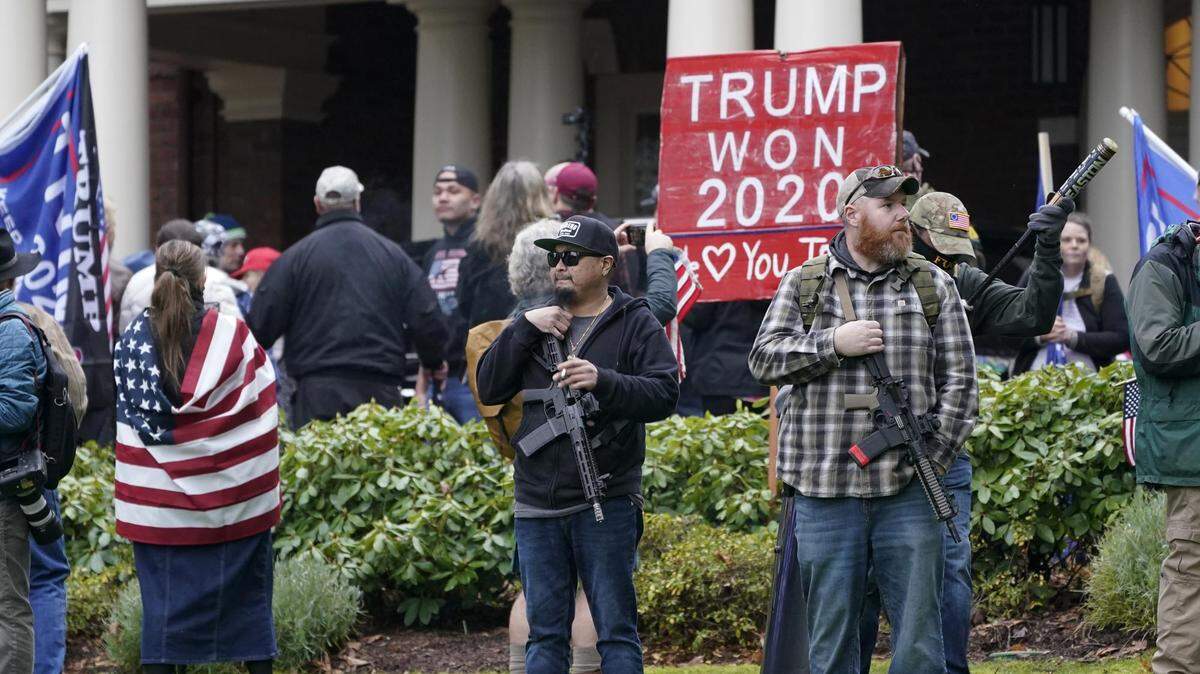 Two men armed with guns on Jan. 6, 2021, stand in front of the Governor’s Mansion in Olympia, Washington, protesting the electoral-vote count in Washington, D.C.