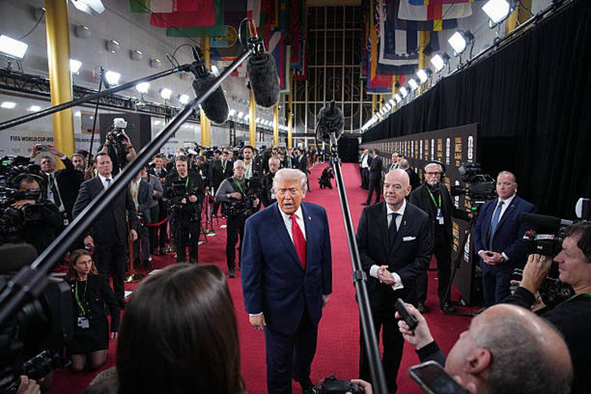 WASHINGTON, DC - DECEMBER 05:  U.S. President Donald Trump answers questions from reporters as he arrives on the red carpet with FIFA President Gianni Infantino (R) for the FIFA World Cup 2026 Official Draw at the John F. Kennedy Center for the Performing Arts December 05, 2025 in Washington, DC.  The 2026 FIFA World Cup will take place between June 11 and July 19 featuring 48 teams with matches being played in the United States, Mexico and Canada, the first time the international sporting event will be hosted by three nations.  (Photo by Andrew Harnik/Getty Images)