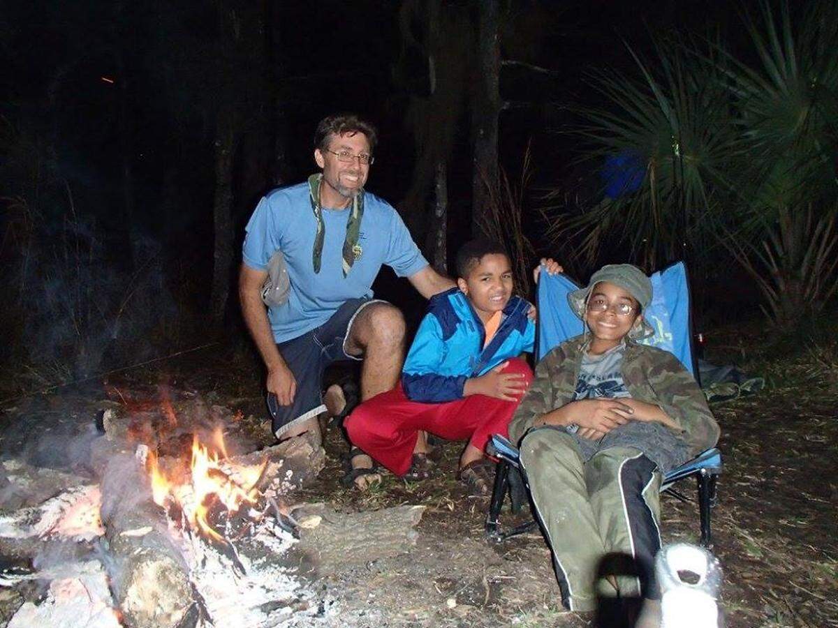 Ariel Poholek and his sons Daniel and Pascal sit by a camp fire in this undated photo from Poholek’s Facebook page.