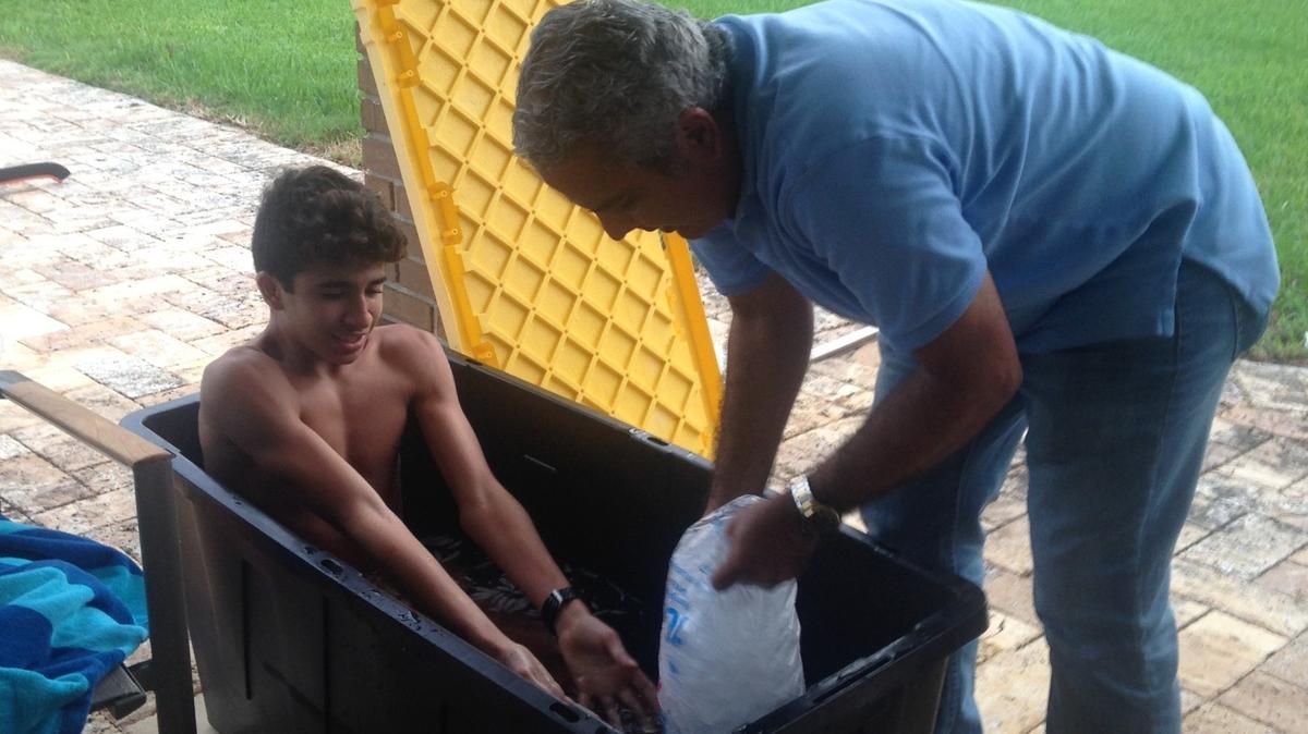 Belen’s cross-country runner Javier Vento, left, takes an ice bath helped by his father, Javier.