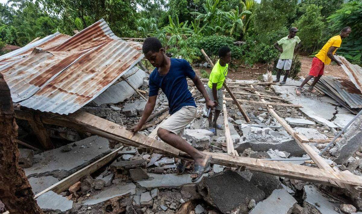 Unos hombres trabajan para salvar la madera y láminas de un tejado derrumbado en Fleurant, Haití, donde muchos de los edificios de la pequeña ciudad quedaron destruidos por el terremoto del 14 de agosto.