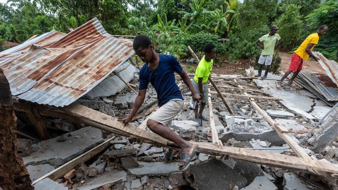Men work to salvage wood and tin from a collapsed roof in Fleurant, Haiti, where many of the small town’s buildings were destroyed by the Aug. 14 earthquake. 