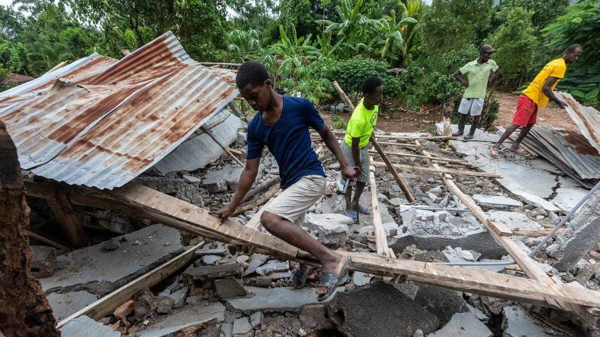 Men work to salvage wood and tin from a collapsed roof in Fleurant, Haiti, where many of the small town’s buildings were destroyed by the Aug. 14 earthquake.