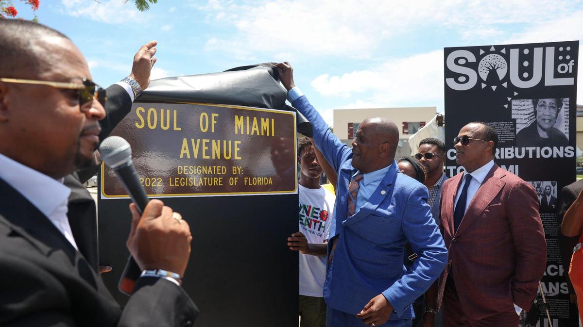 El pastor Gaston Smith (izquierda) habla mientras el representante estatal James Bush III devela en junio de 2022 cómo lucirá el nuevo letrero de Soul of Miami Avenue en Liberty City.