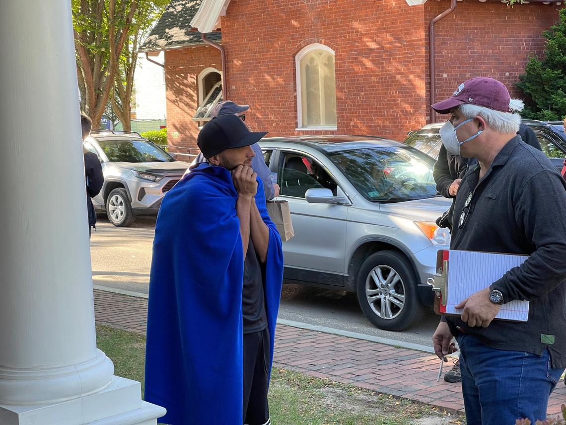 A translator speaks with a young man, draped in one of the blankets donated for migrants, in Edgartown, Mass., on Martha’s Vineyard, Wednesday, Sept. 14, 2022.