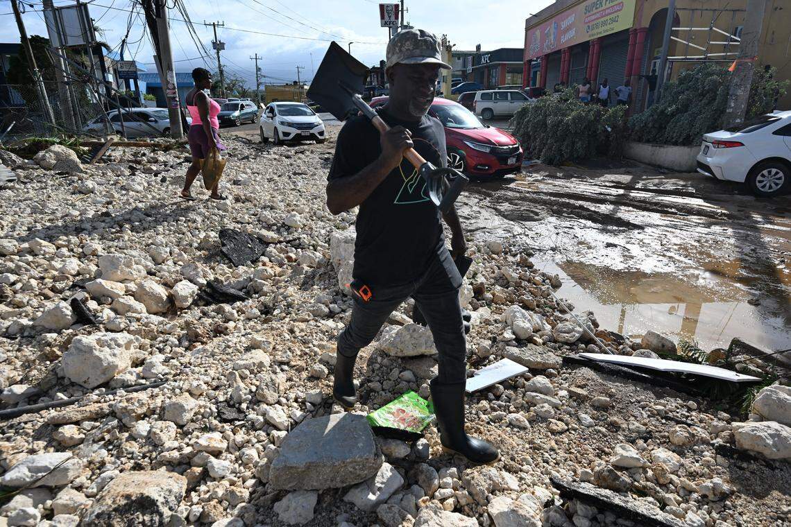 A man walks with a shovel in hand over rubble on Main Street in Santa Cruz, St. Elizabeth, Jamaica on October 29, 2025. Hurricane Melissa ripped up trees and knocked out power after making landfall in Jamaica on October 28, 2025 as one of the most powerful hurricanes on record, inundating the island nation with rains that threaten flash floods and landslides.
