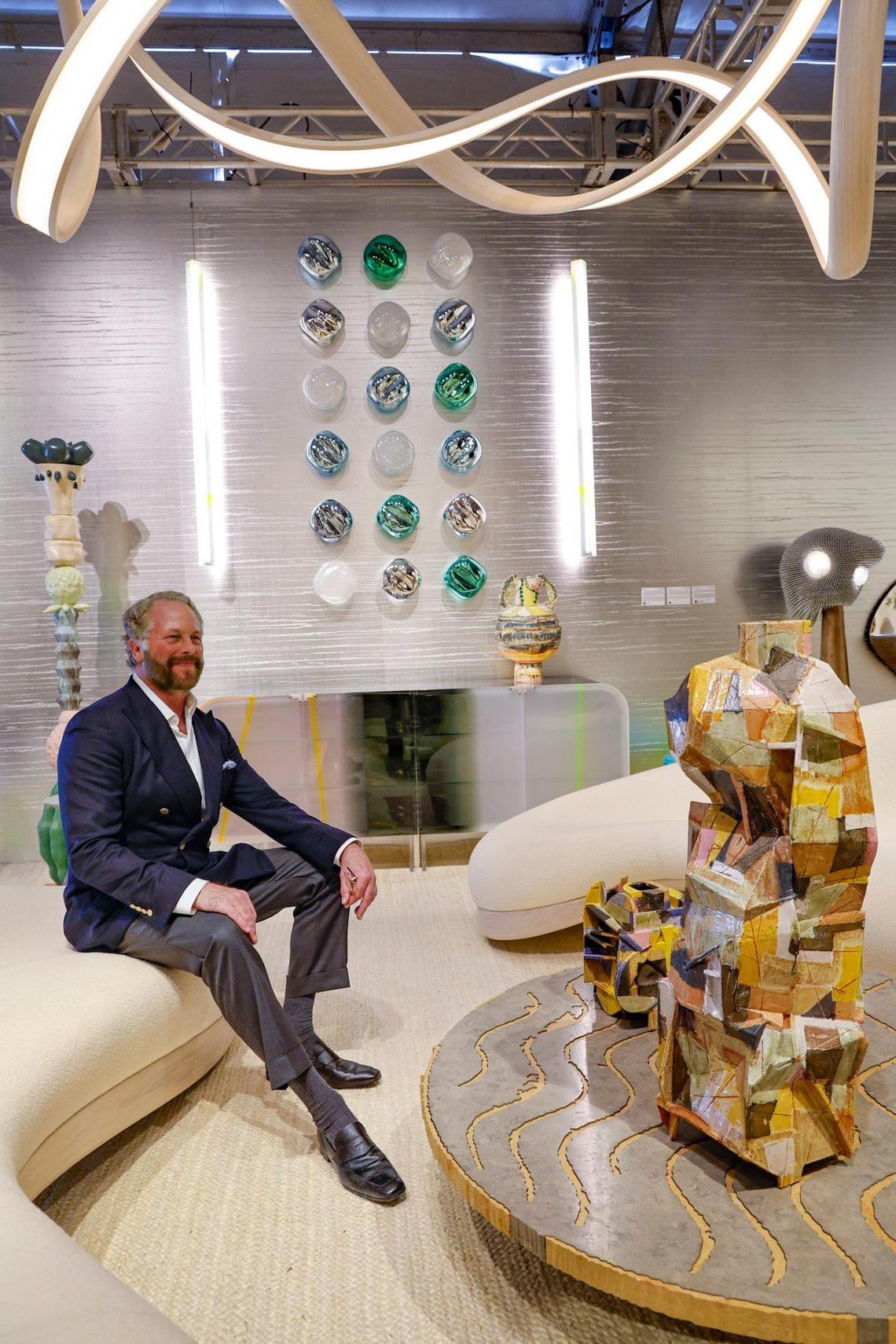 Todd Merrill with Todd Merrill Studio, sits on designer John Procario’s free form sofa surrounded by work by artists Hervé Obligi, Christopher Russell and Draga & Aurel among others at Design Miami on Miami Beach, Florida on Tuesday, December 3, 2024.