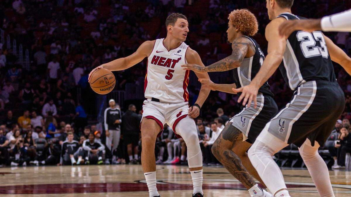Miami Heat forward Nikola Jovic (5) dribbles while defended by San Antonio Spurs forward Jeremy Sochan (10) during the second quarter of an NBA preseason game at Kaseya Center on October 15, 2024, in Miami.