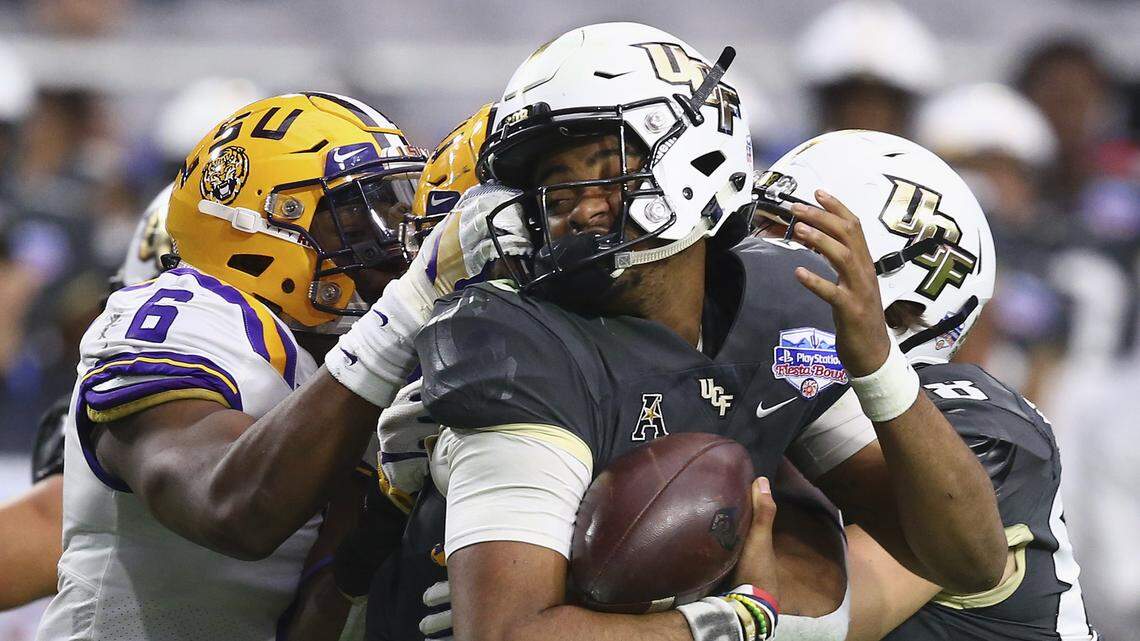 UCF quarterback Darriel Mack Jr., middle, gets his face mask pulled by LSU linebacker Jacob Phillips (6) as UCF tight end Jake Hescock, right, attempts to make a block during the second half of the Fiesta Bowl NCAA college football game Tuesday, Jan. 1, 2019, in Glendale, Ariz. LSU defeated UCF 40-32.
