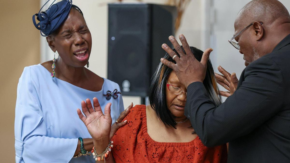 Cecily Robinson-Duffie, left, in the blue dress, joins in prayer over a parishioner with her husband Troy Duffie, right, during a Sunday service at St. John Institutional Missionary Baptist Church in Overtown. The church is facing a foreclosure lawsuit over a $1.6 million mortgage taken out by its former pastor, Bishop James D. Adams.