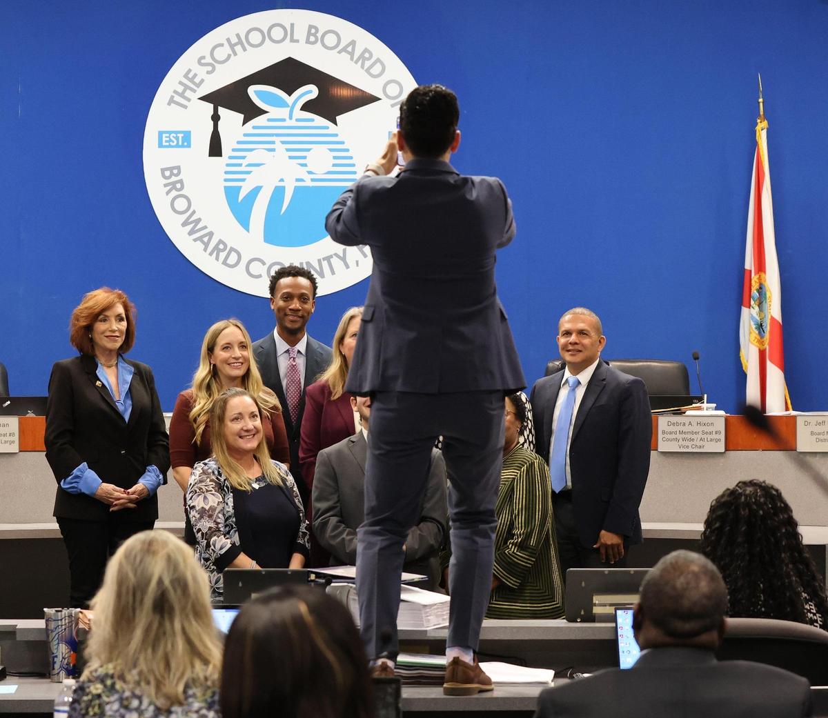 John Sullivan, district spokesman, center, takes a photo of the board members with Jorge Altuna, student advisor who is leaving his post on Tuesday, May 9, 2023, in Fort Lauderdale, Florida.