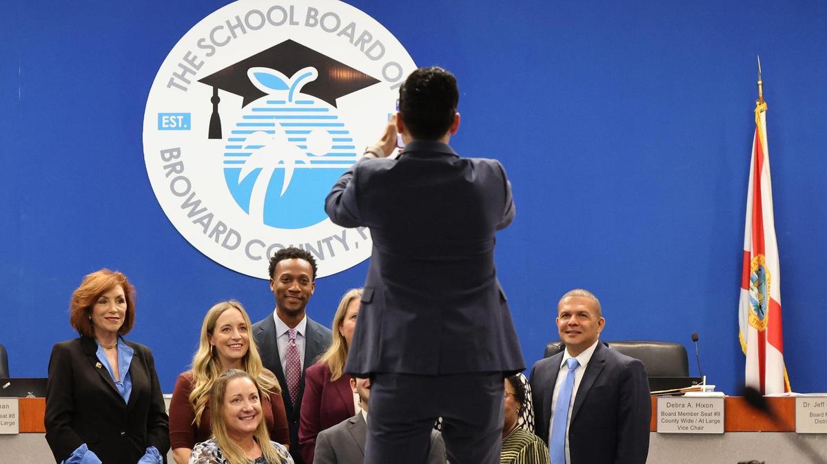 John Sullivan, district spokesman, center, takes a photo of the board members with Jorge Altuna, student advisor who is leaving his post on Tuesday, May 9, 2023, in Fort Lauderdale, Florida.