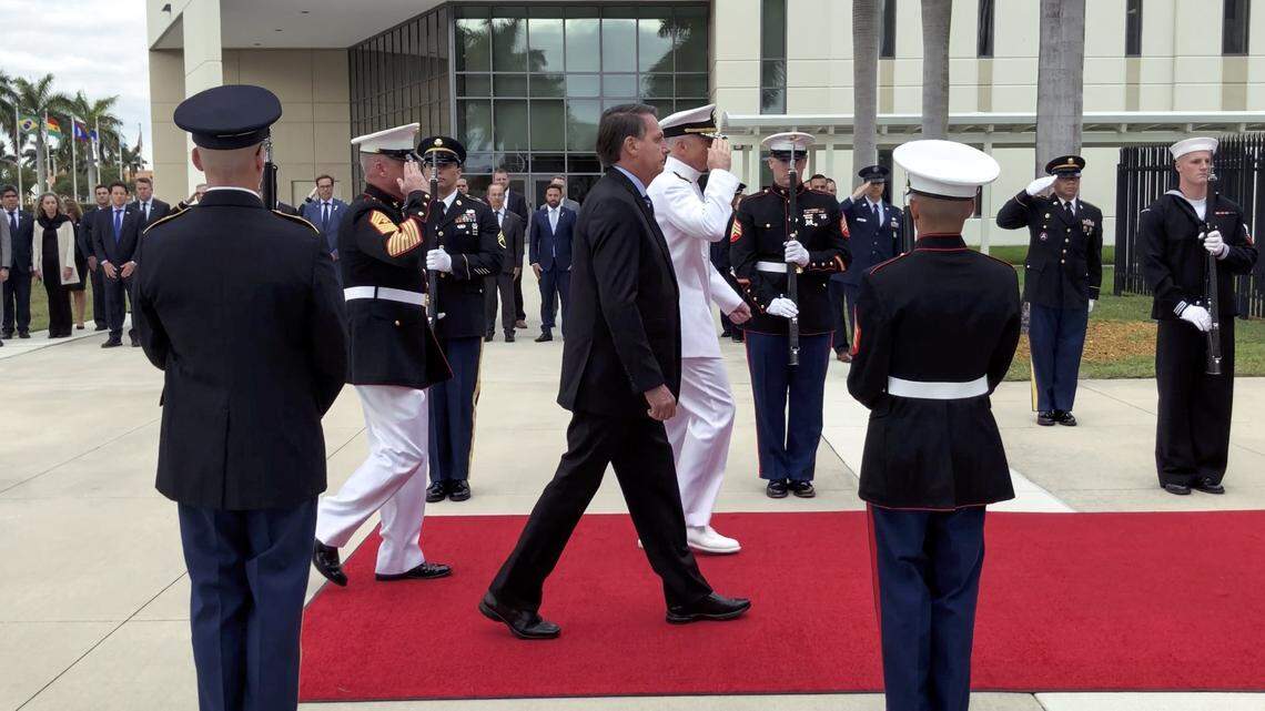 In a file photo, Brazilian President Jair Bolsonaro, center, walks alongside U.S. Navy Adm. Craig Faller, commander of the U.S. Southern Command, on the ceremonial red carpet during the historic first visit to the U.S. Southern Command to be present for the signing of a bilateral Agreement on Research Development, Test, and Evaluation Projects on Sunday, March 8, 2020, in Doral, Florida.