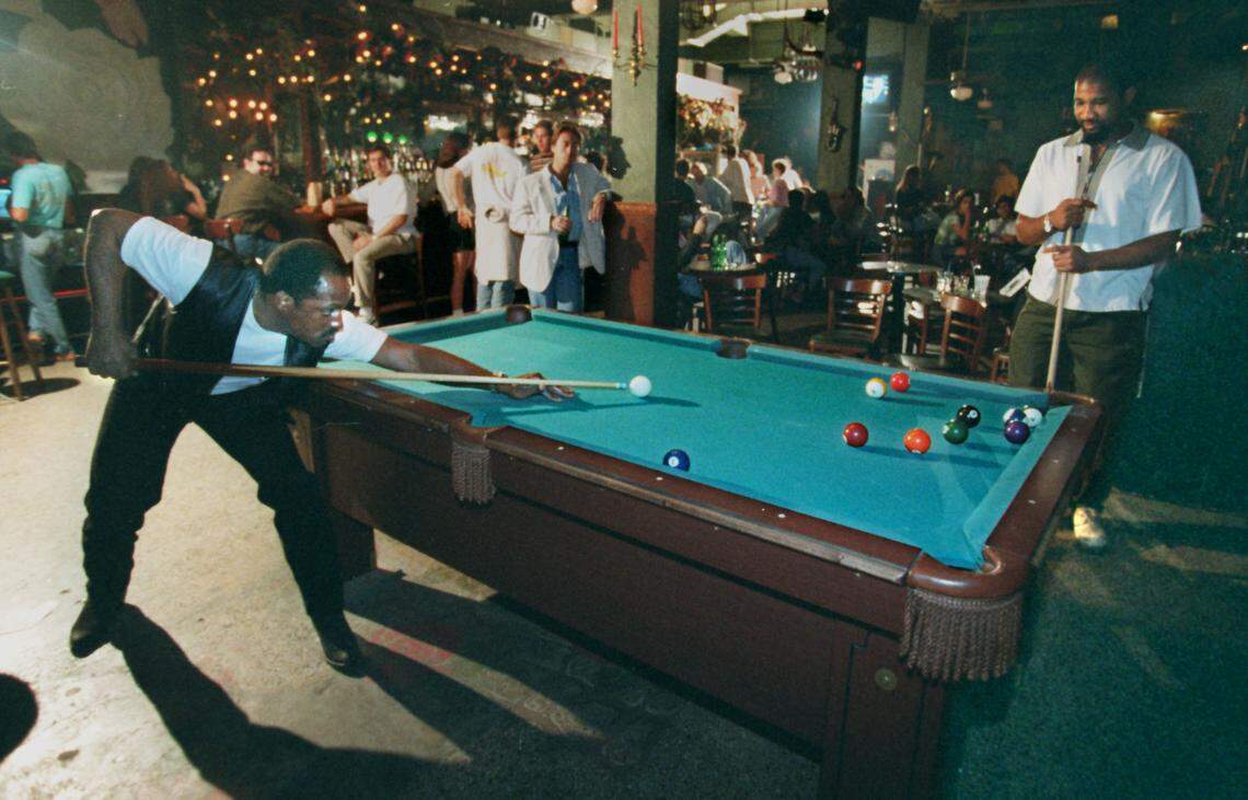 Rose’s Bar regular Sam Pink shoots pool with the club’s manager and booking agent Jacques Milhomme on March 23, 1995.