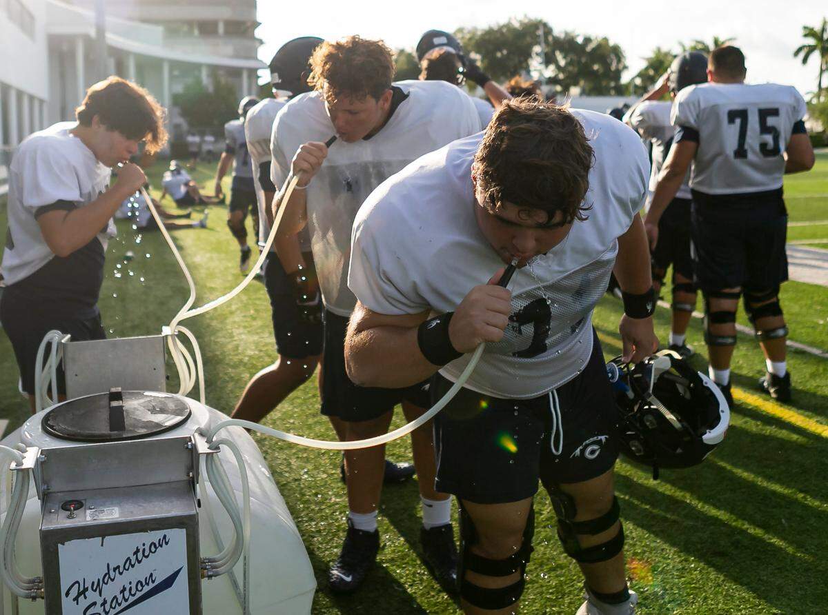 Christopher Columbus players take a water break as they attend a preseason practice at their school in Miami’s Westchester neighborhood on Wednesday, August 4, 2021.