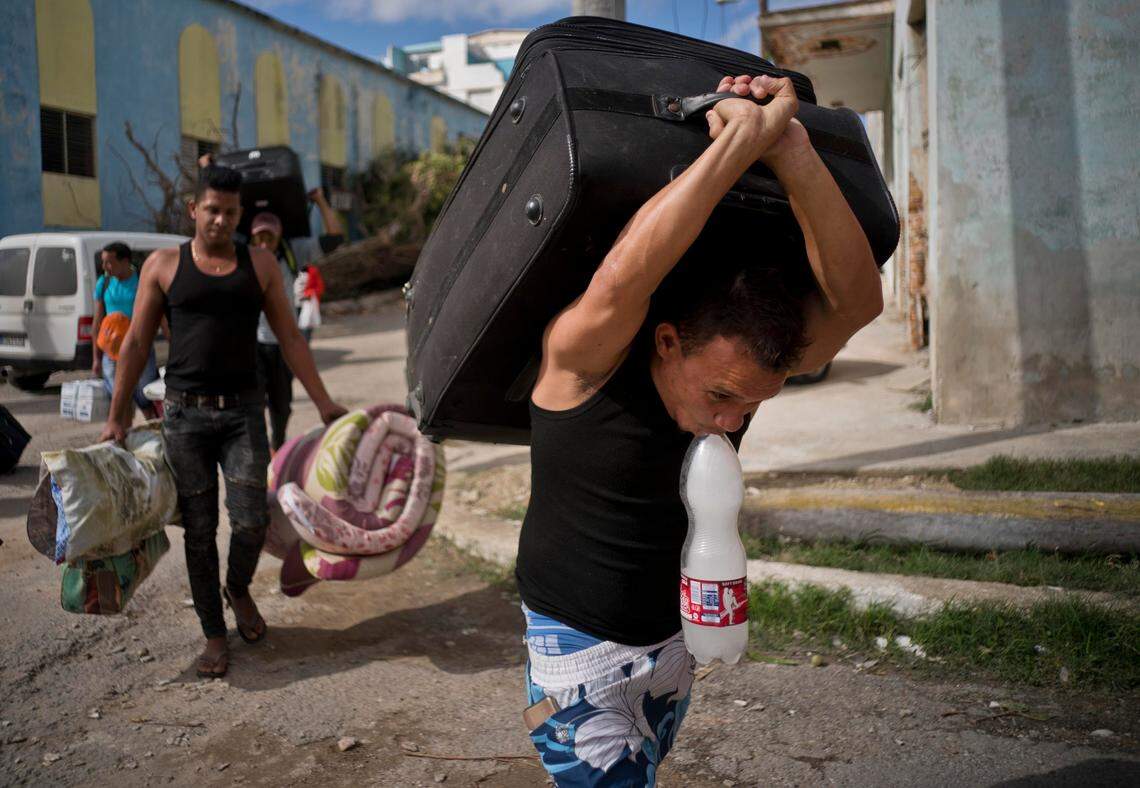 People whose homes were damaged by a tornado carry their belongings to be taken by bus to a Havana shelter.