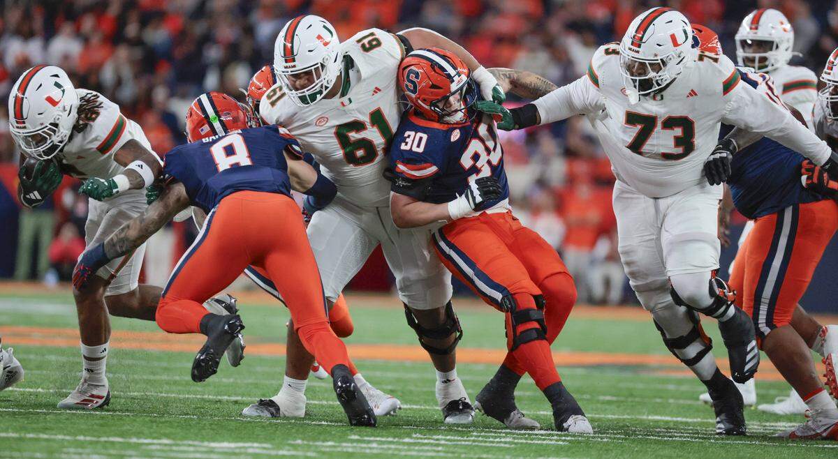 Miami Hurricanes running back Damien Martinez (6) on a carry as Miami Hurricanes offensive lineman Francis Mauigoa (61) and Miami Hurricanes offensive lineman Anez Cooper (73) clear a path against Syracuse Orange defenders in the first half of their NCAA football game in the JMA Wireless Dome at Syracuse University, Syracuse, New York on Saturday, November 30, 2024. 
