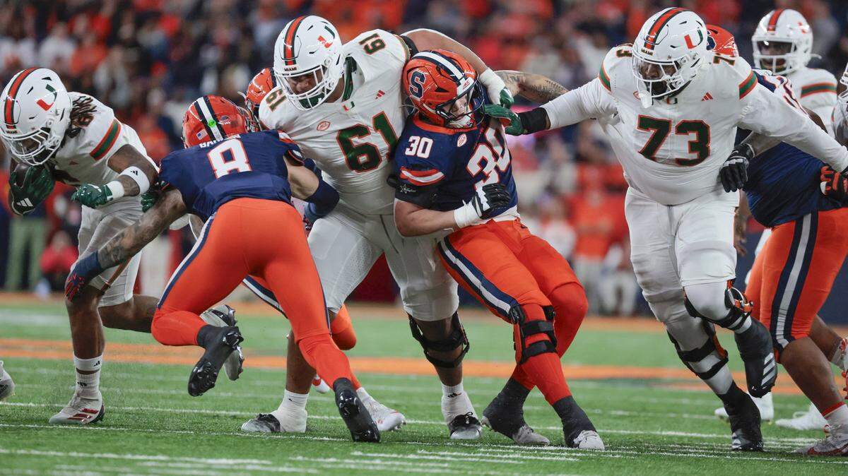 Miami Hurricanes running back Damien Martinez (6) on a carry as Miami Hurricanes offensive lineman Francis Mauigoa (61) and Miami Hurricanes offensive lineman Anez Cooper (73) clear a path against Syracuse Orange defenders in the first half of their NCAA football game in the JMA Wireless Dome at Syracuse University, Syracuse, New York on Saturday, November 30, 2024. 