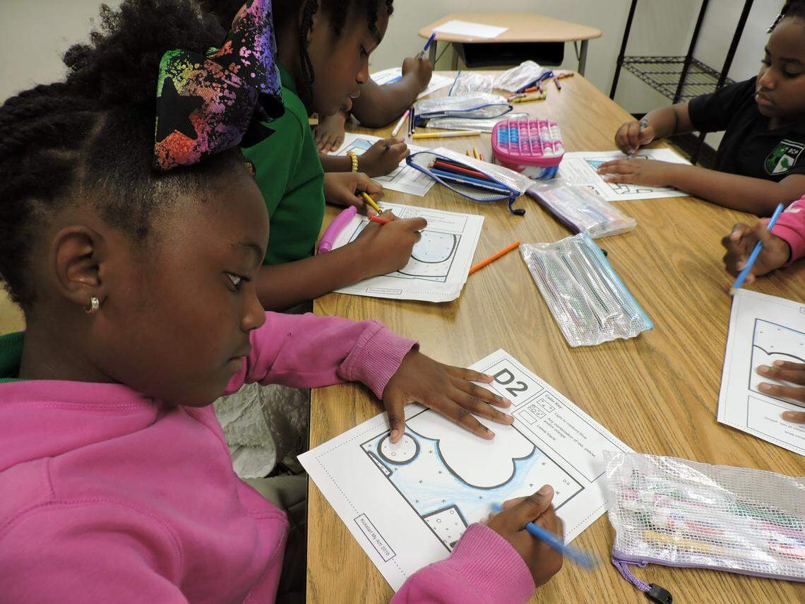 Taraji Kennedy, in pink, and Melanie Ponder and Treneice McKenzie color puzzle pieces as part of a Girls Inc. after-school program on Oct. 6, 2022, at Beacon College Preparatory in Opa-locka.