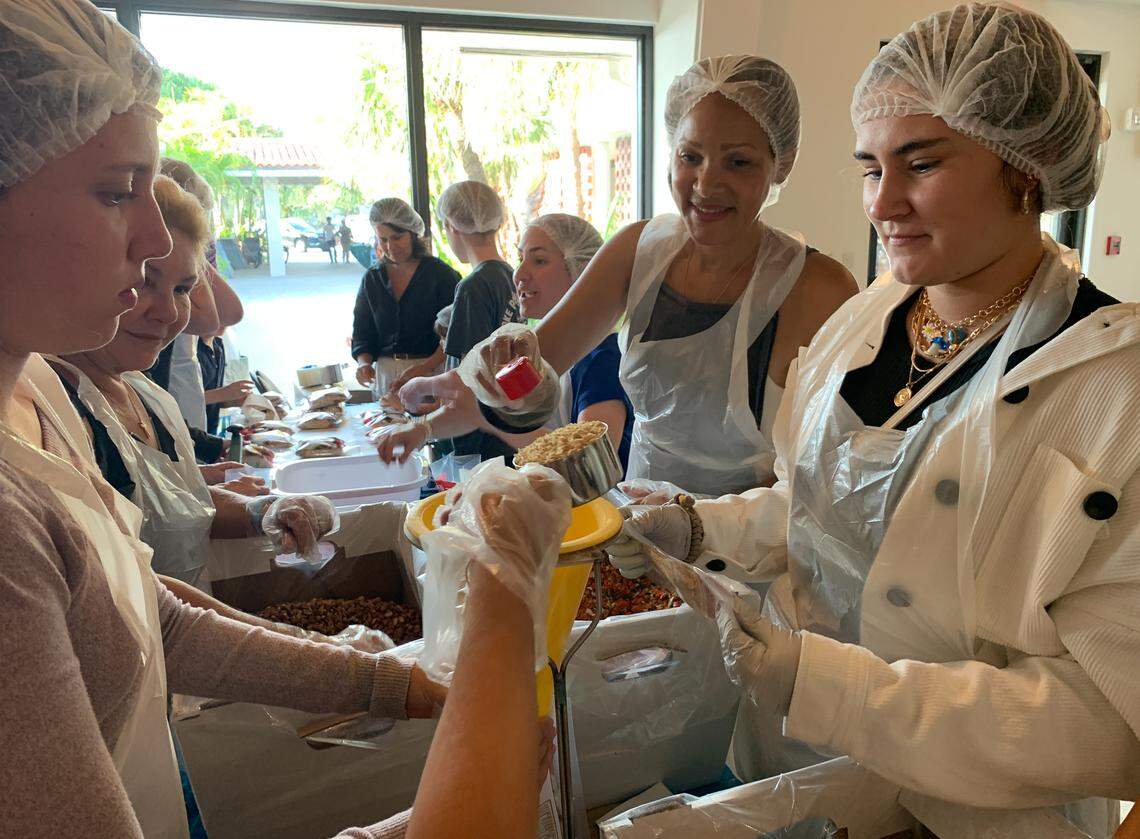 Krista Alles, 22, a member of St. Augustine’s young adult ministry and Mia, 50, help prepare food packages as part of an event at St. Augustine Catholic Church in Coral Gables on Friday, April 1, 2022.