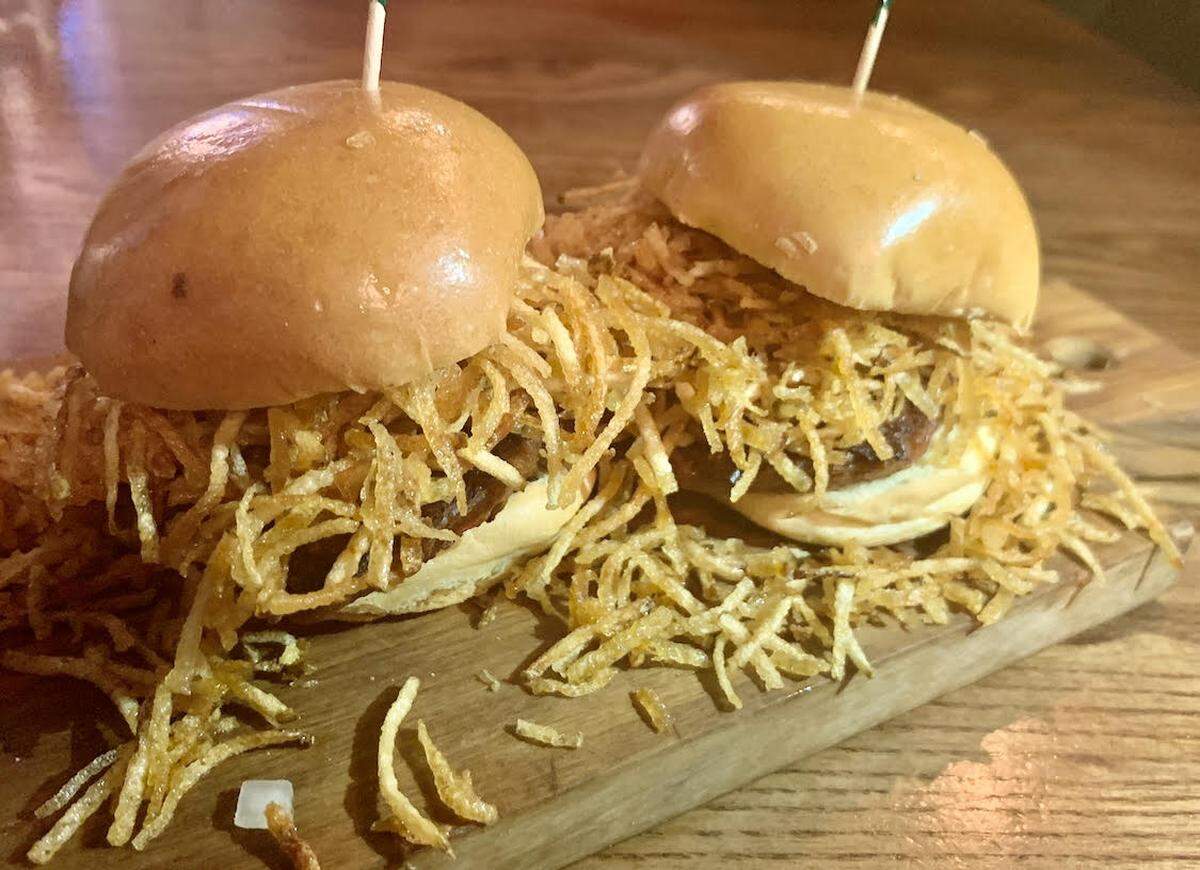 La Flaca Plant-based Frita is served with onions, potato springs and ketchup. It’s topped with a “vegan bun.”