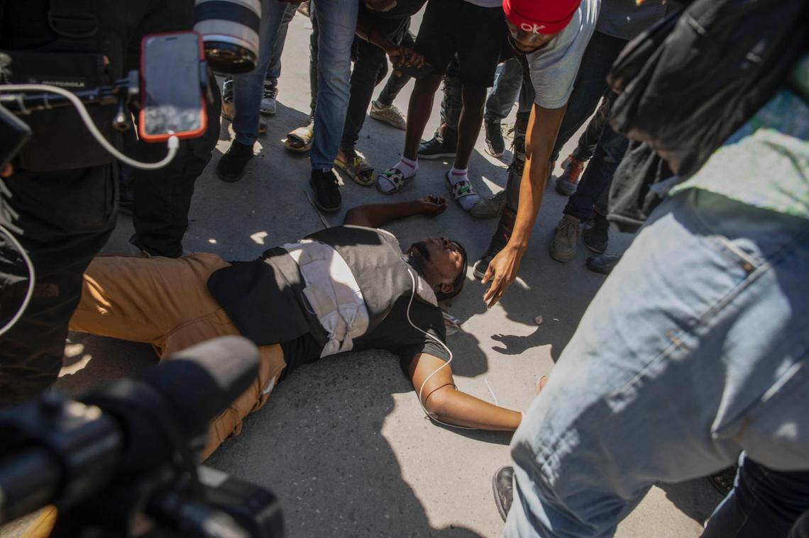 A Haitian photojournalist lies dead on the ground after he was shot while covering a protest by factory workers demanding higher salaries in Port-au-Prince, Haiti, Wednesday, Feb. 23, 2022. The journalist, initially identified as Maxihen Lazarre but whose first name is Maxiben, was covering the demonstration when men wearing police uniforms drove by the protest and fired into the crowd of protesters.