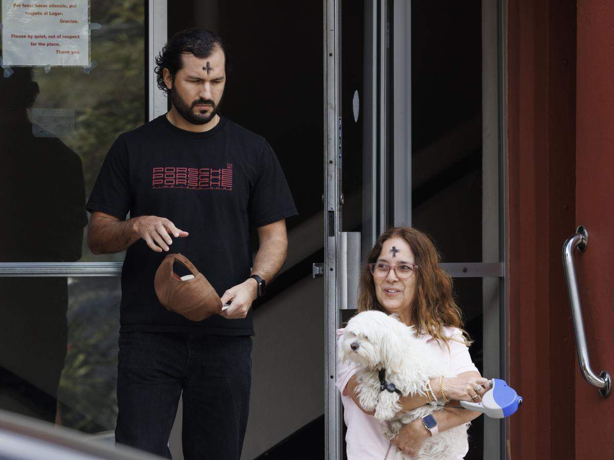 Raul Chirinos, left, and Olga Elena Landazuri, with dog Toty, walk out of Ash Wednesday mass on Wednesday, Feb. 18, 2026, at Gesu Catholic Church in downtown Miami. 